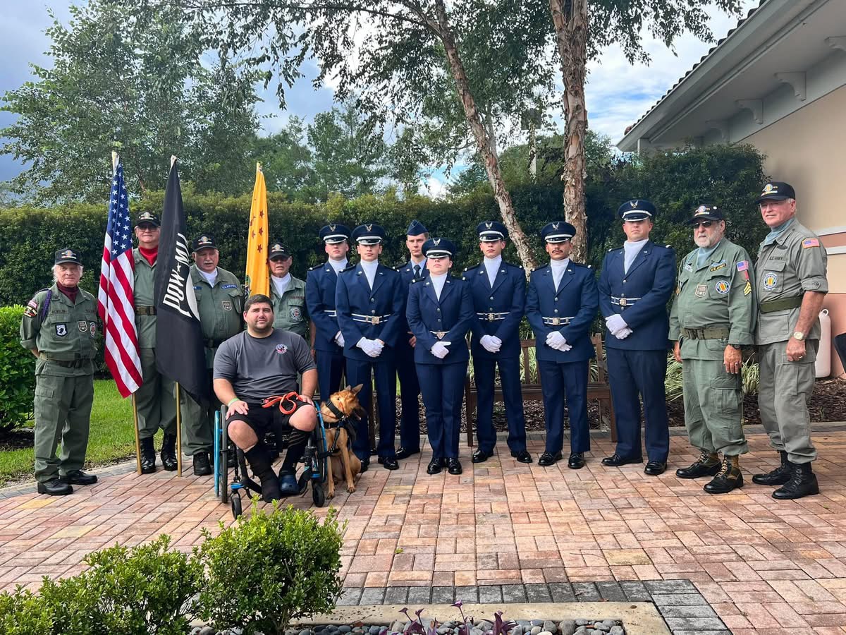 Old Glory member and service dog with military honor guard members at a community event"